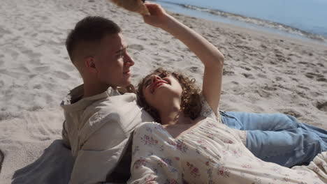 carefree couple lying sand beach summer time close up. girl putting hat on man.