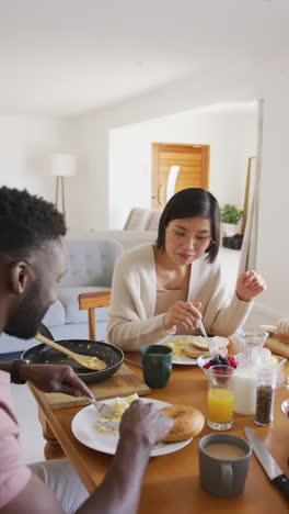 vertical video of happy diverse couple at table having breakfast