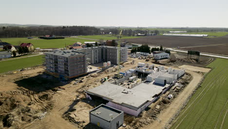 aerial view showing large construction area build apartment blocks in rural residential area during sunlight