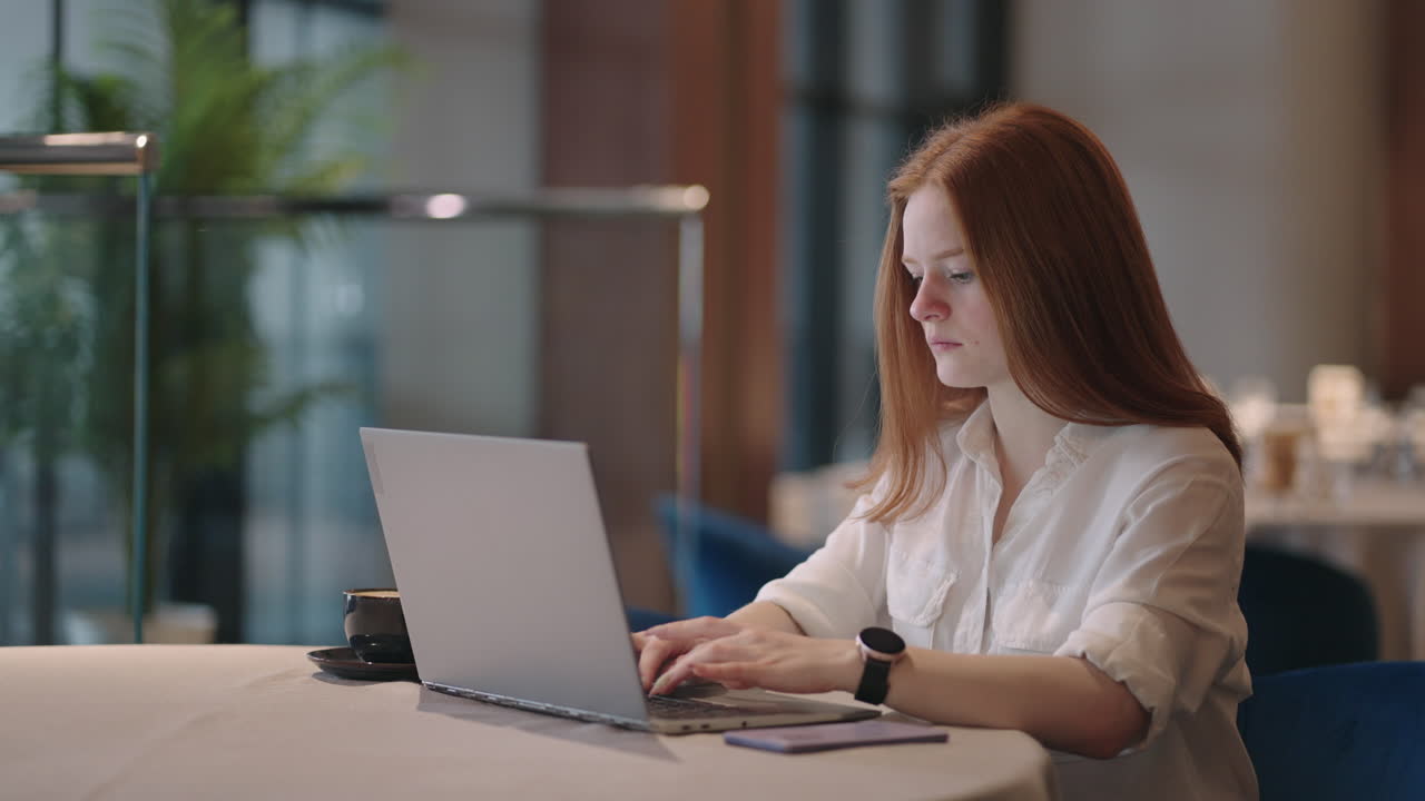 Young Red-haired female professional writing an important email from her home. Modern living room. Remote working. serious woman search for inspiration make decision feel lack of ideas