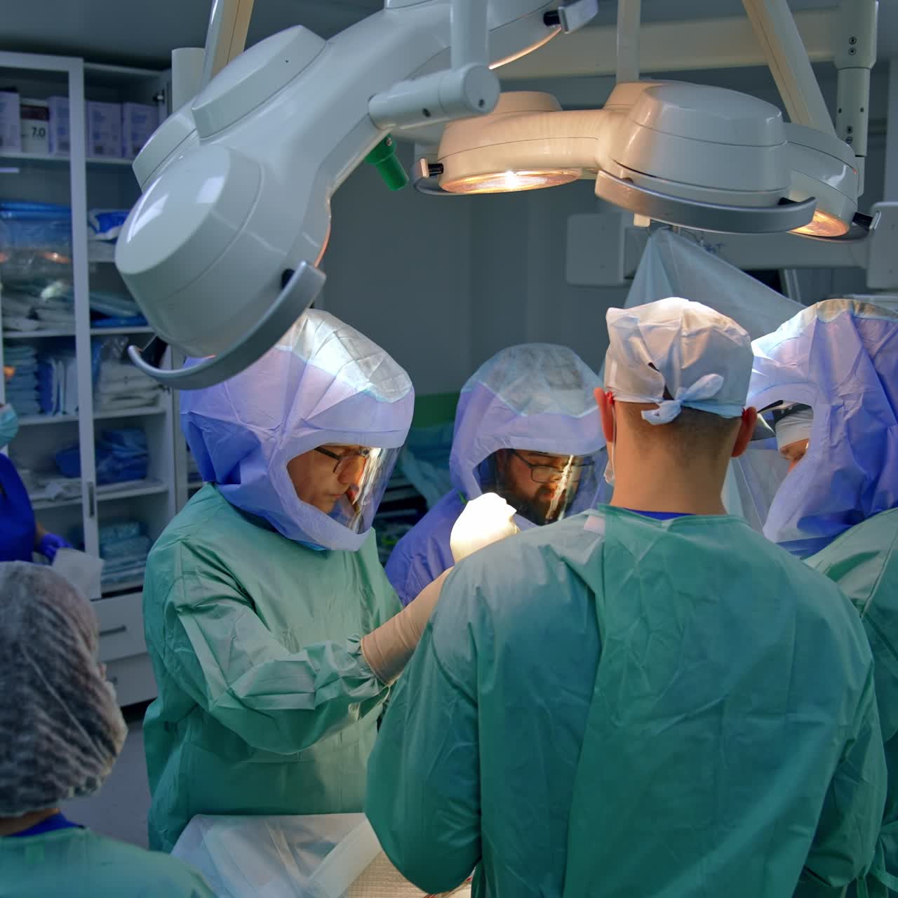 One of the surgeons in doctoral team holding the foot of a patient. Group of medics perform trauma surgery
