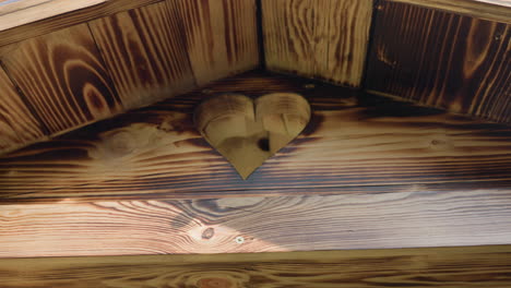 heart shaped cutout on wooden building rooftop surrounded by rich wood grain and sunlit textures, highlighting warm rustic craftsmanship and natural patterns with screw details