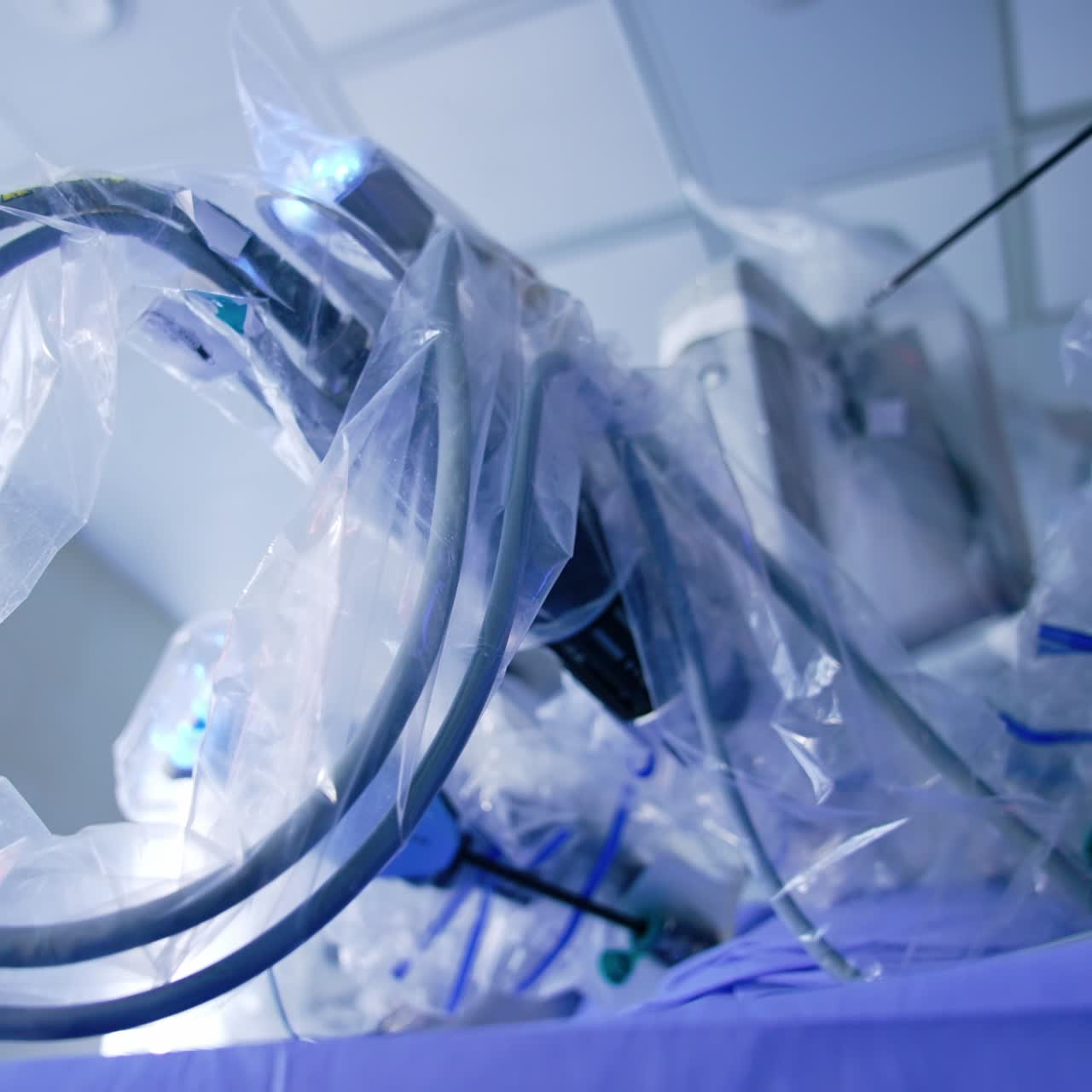 Moving arms of the robotic surgeon covered in plastic for sterility. Da Vinci robot carries out the laparoscopy. Low angle view