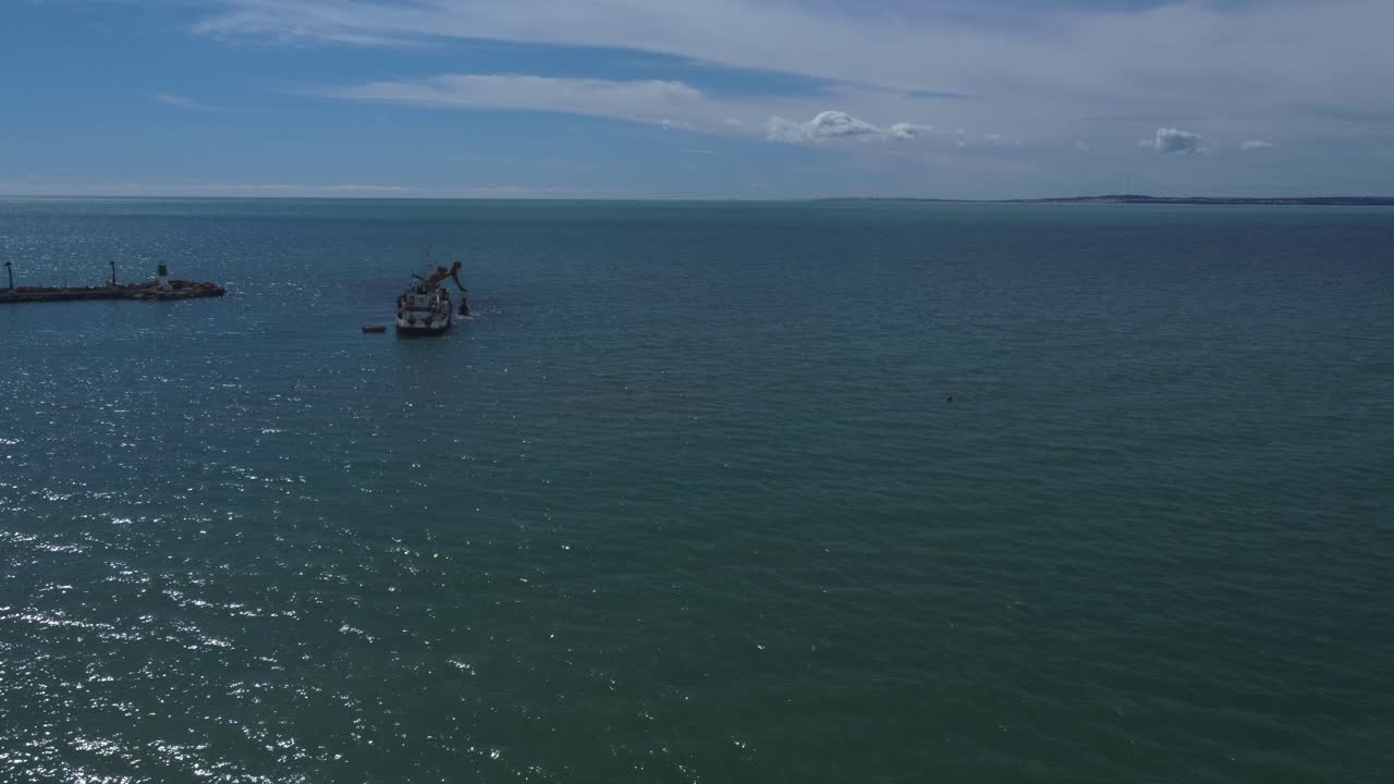 Aerial approach to a boat dredging the entrance of a port, Santa Pola, Spain