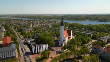 aerial shot of the city church siauliai, cathedral of saints peter and paul, on a sunny day by the river siauliai, lithuania, zoom in