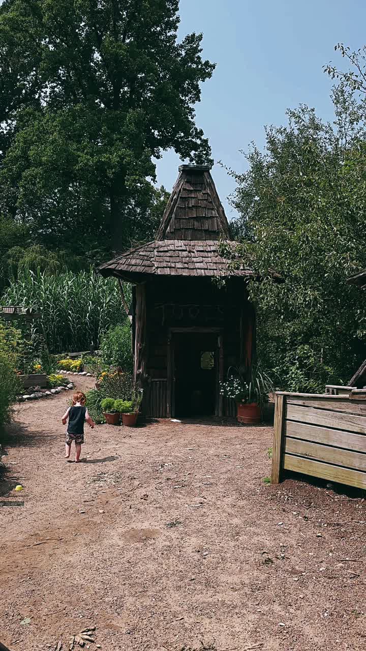 niño jugando cerca de una casa de juegos de madera en un jardín