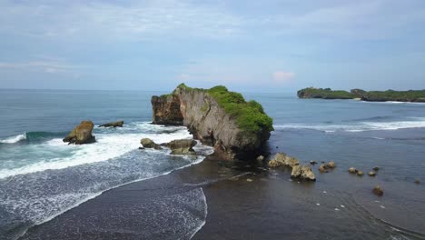 Aerial-view-of-rock-on-shoreline-of-tropical-beach-with-coral-island-in-Indonesia