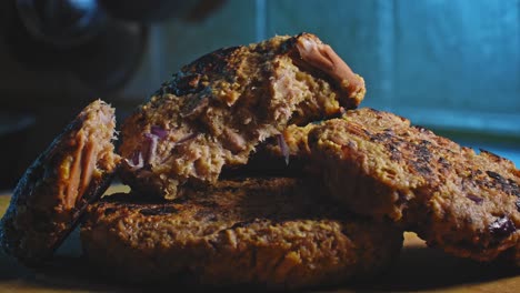 Primer-Plano-De-Deliciosos-Buñuelos-De-Atún-Apilados-Uno-Encima-Del-Otro-En-Una-Encimera-De-Cocina-Con-Fondo-Azul