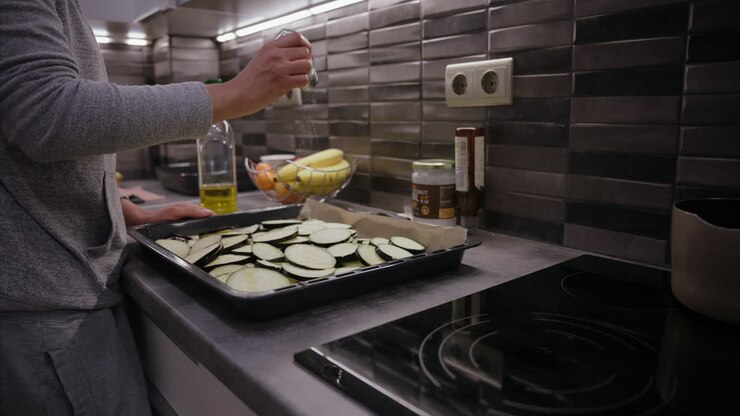 Woman seasoning sliced eggplant with salt on a baking sheet in the kitchen, vegetable, fruit, cooking homemade healthy lunch, dinner, kitchen, organic fruits, vegetables olive oil, coconut oil, vegan