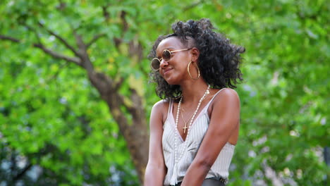 Moda-Joven-Mujer-Negra-Con-Gafas-De-Sol-Redondas-Y-Camisola-Divirtiéndose-Y-Riendo-Al-Aire-Libre,-Cerrar