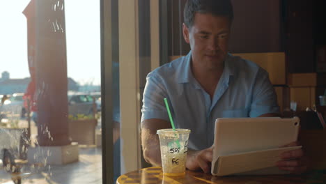 man using tablet computer in cafe