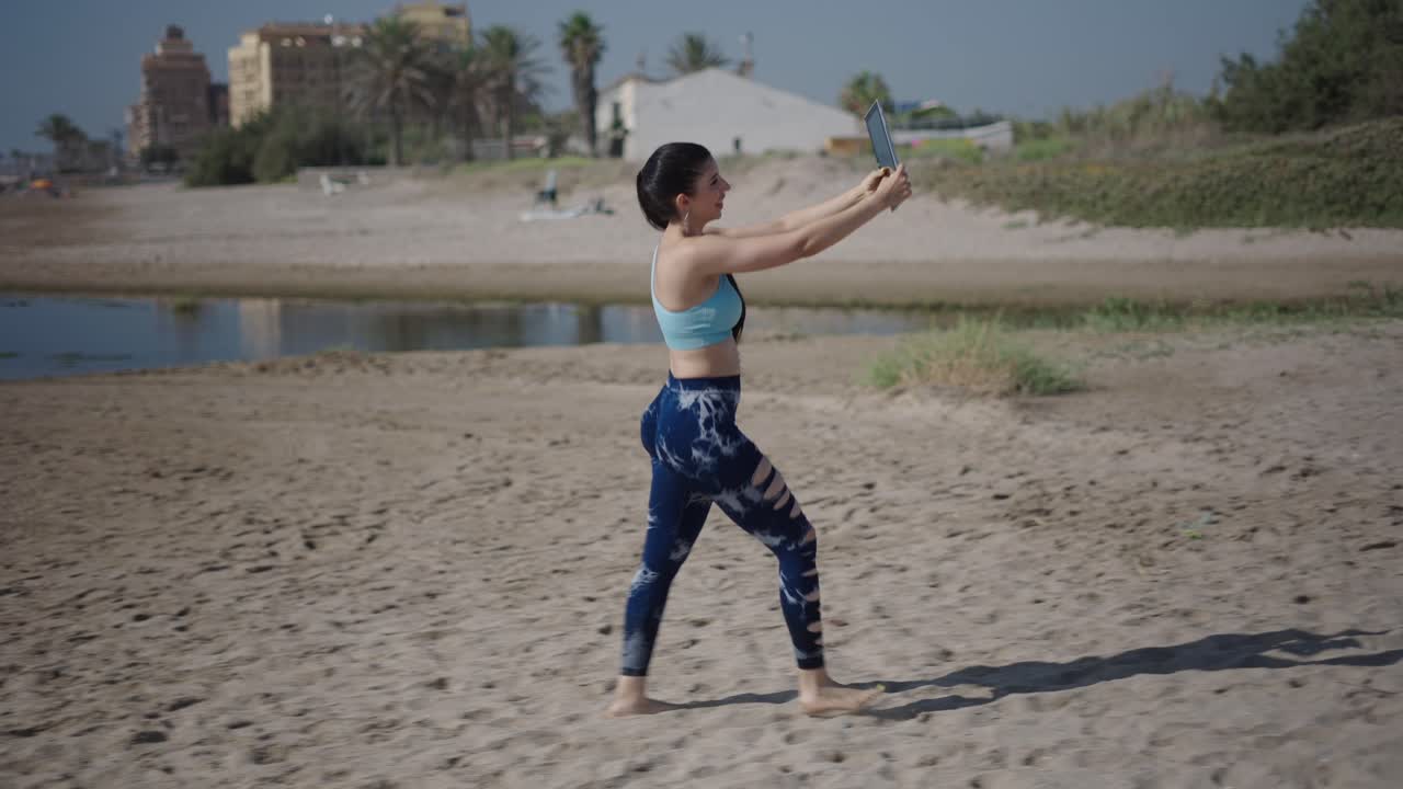 Woman taking a selfie on a beach while running