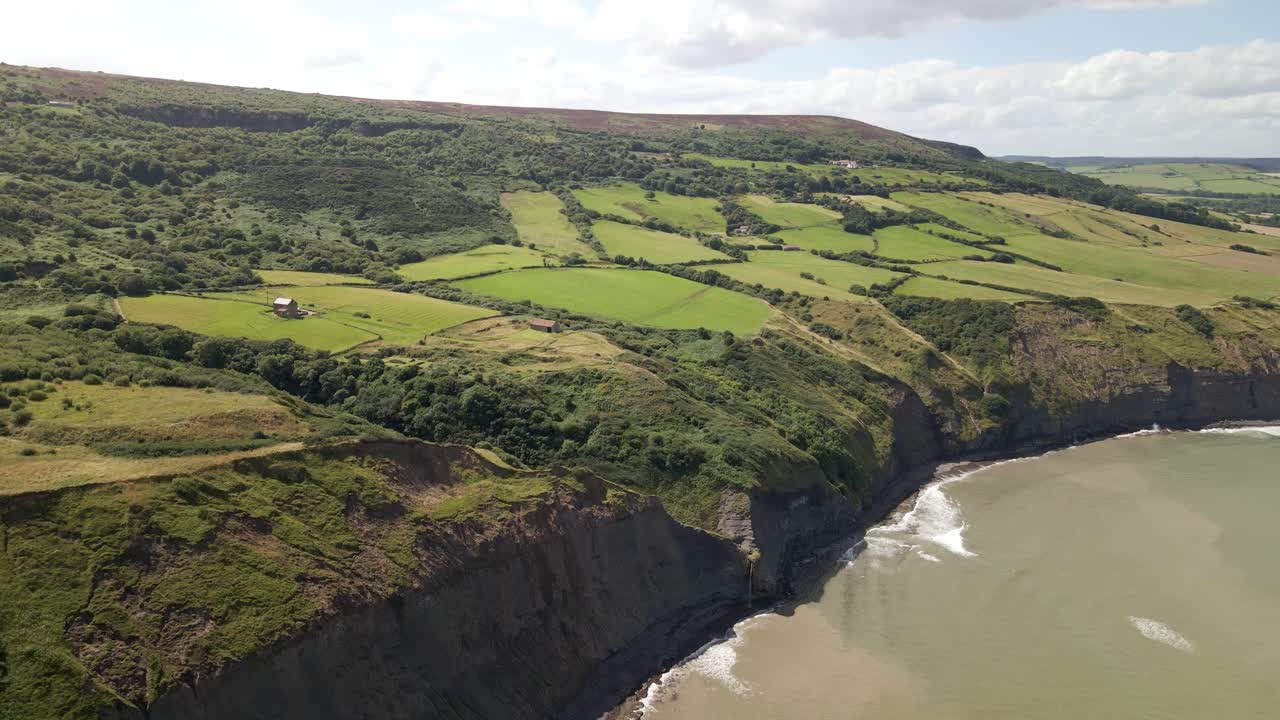 tomada aérea de drones de la costa de north yorkshire cerca de ravenscar con campos verdes y océano