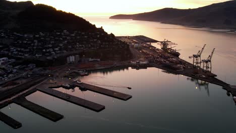 Sunrise-over-port-surrounded-by-mountains-aerial-Lyttelton,-New-Zealand