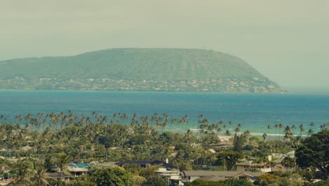 Toma-Estática-Con-Vista-A-La-Isla-Con-Un-Pueblo-Costero-En-Primer-Plano-Y-Una-Playa-Bordeada-De-Palmeras.