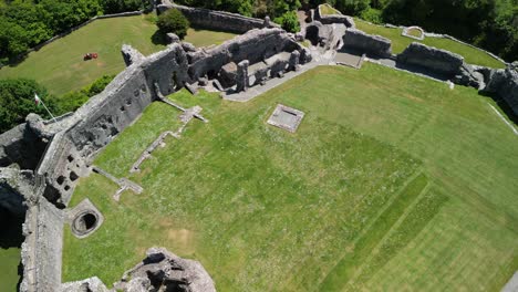 Denbigh-Castle-and-Town-Walls,-Denbighshire,-Wales---Aerial-drone-gimbal-down-flyover-and-rotate,-castle-reveal---June-23