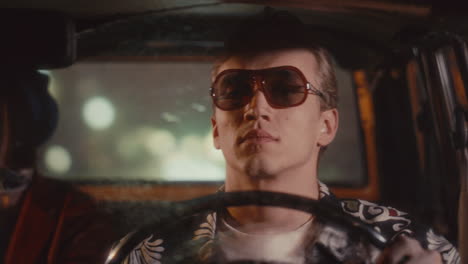 man in sunglasses driving retro taxi cab on rainy night