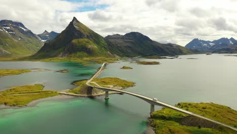 drone shot from camper driving over bridge in lofoten norway with mountains in the background