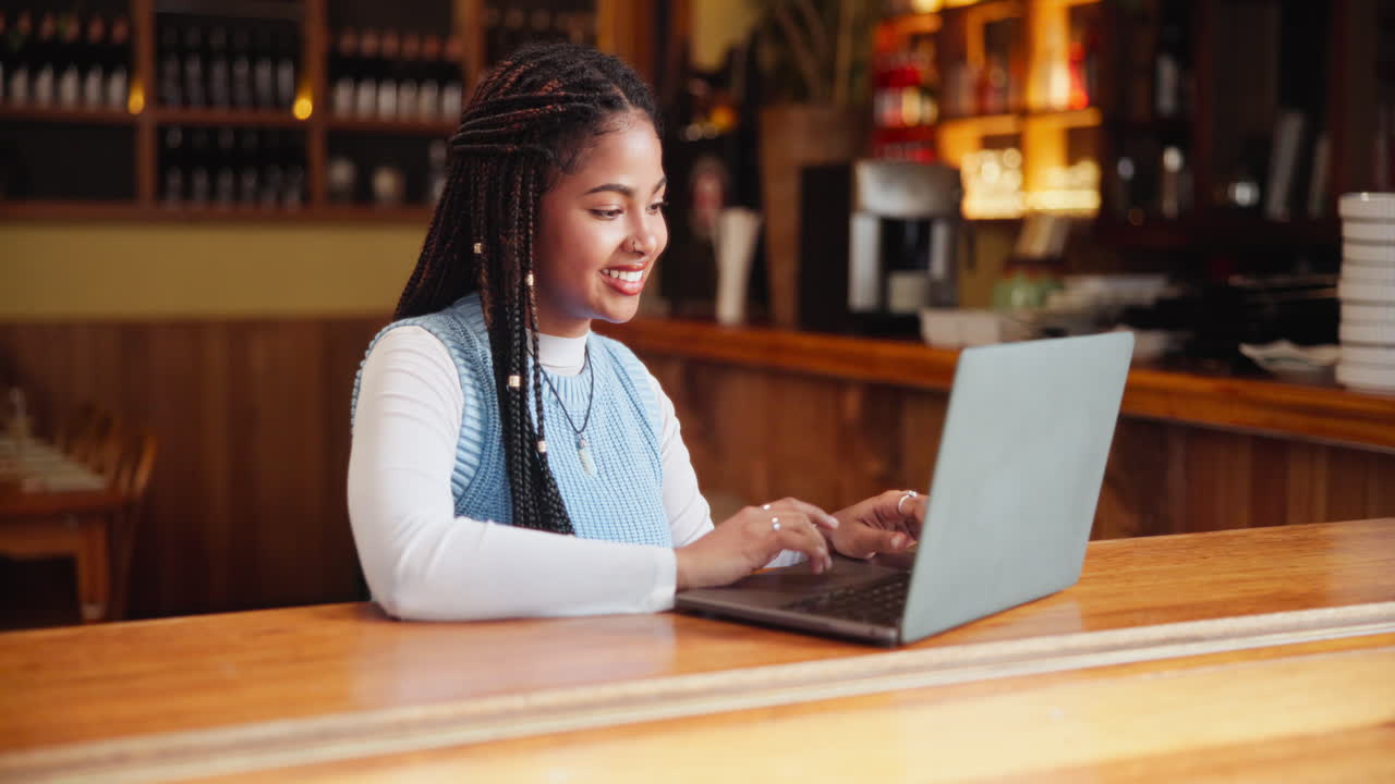 Woman working on a laptop at a cafe bar