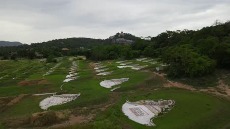 aerial footage towards the hill where wat phra phutthachai is, a buddhist temple, also revealing a chinese cemetery, saraburi, thailand.