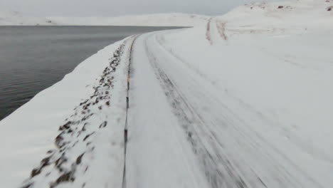 snowy country road along ocean shore, dolly forward