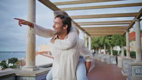 active pair piggybacking together summer park. happy man carrying overjoyed lady