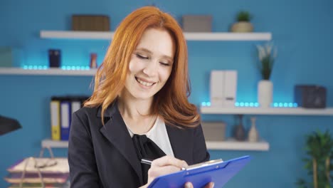 mujer de negocios dirigiéndose a la cámara y tomando notas en el cuaderno.