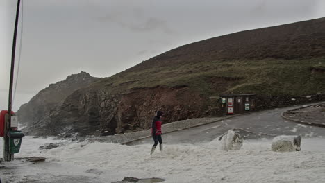 woman on snow-covered chapel porth beach as winter storm eunice hits cornwall coast in uk