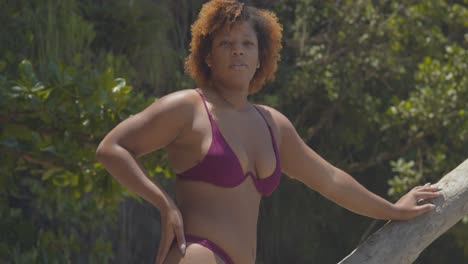 chica de la isla tropical en bikini de pie en la arena con el pelo soplando en el viento en la playa