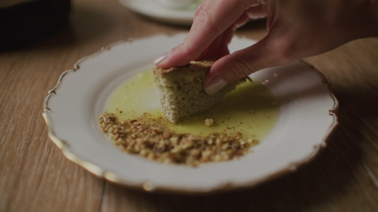 Woman dipping bread in olive oil with nuts