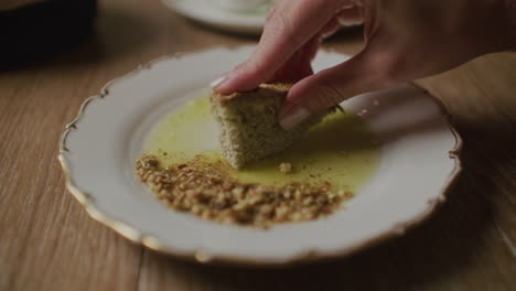 woman dipping bread in olive oil with nuts