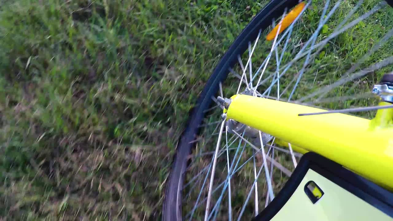Riding a yellow bike in the green grass of the park.