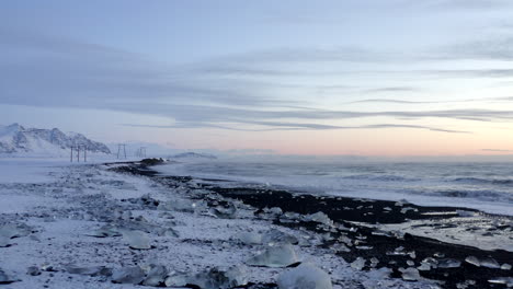 Antena:-Volando-Sobre-La-Playa-De-Diamantes,-Playa-Negra-En-Islandia-En-Invierno,-Nieve,-Hielo,-Olas,-Agua