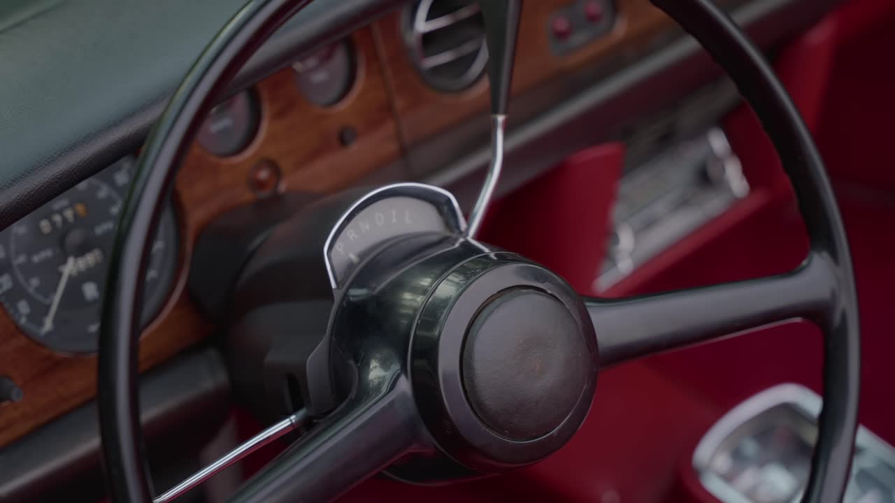 Vista detallada del volante de un coche clásico con madera e interior de cuero rojo
