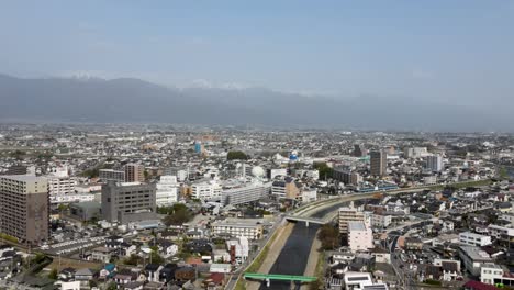aerial view of matsumoto city in nagano prefecture with snow capped mountains in the distant background. dolly forward