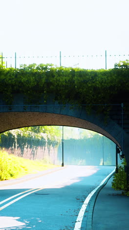 a road going under a brick archway covered in green leaves