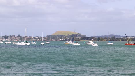 Una-Toma-Manual-De-Un-Grupo-De-Barcos-Flotando-En-Un-Lago-Con-El-Volcán-Monte-Wellington-Al-Fondo-En-Auckland,-Nueva-Zelanda,-En-Un-Día-Ventoso-Y-Nublado