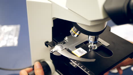 un científico que examina un portaobjetos de células humanas con un microscopio en un laboratorio de ciencias de la investigación médica