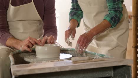 Mid-section-of-male-potter-assisting-female-potter