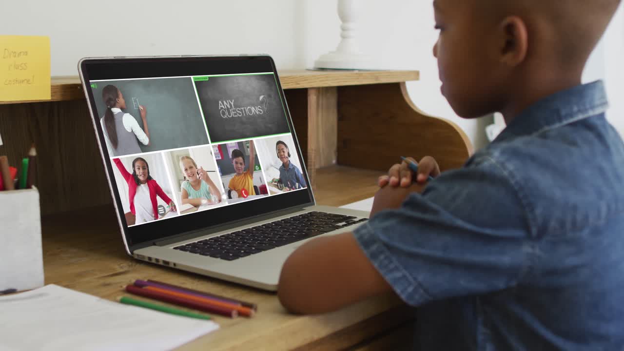Schoolboy using laptop for online lesson at home, with diverse teacher and class on screen