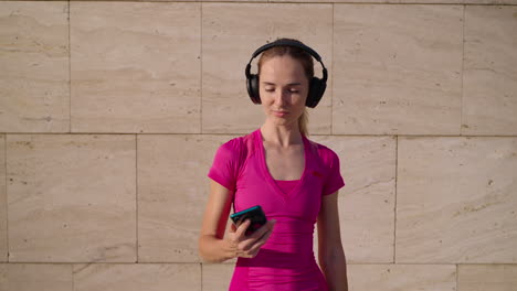 woman using phone while wearing headphones