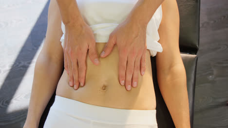 physiotherapist giving stomach massage to a female patient