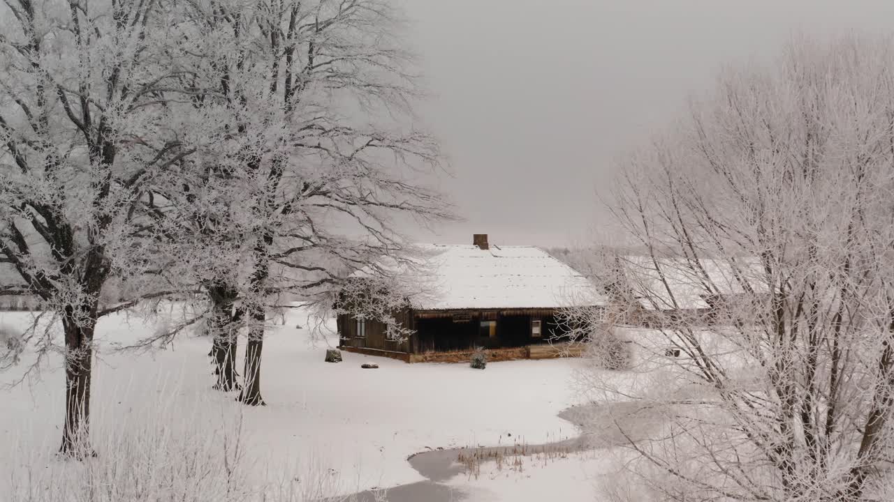 Winter wonderland view of a family house in the countryside with lots of snow on the ground and frost on the trees. Drone shot around a historic property in suburbs. Winter scenery after cold weather.