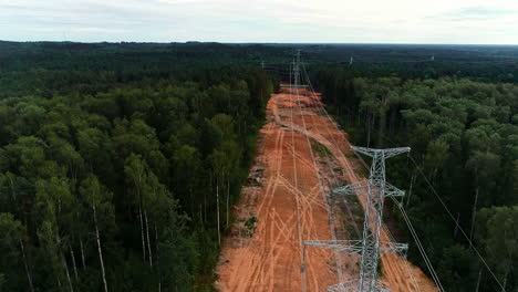 aerial flyover connected electricity pylons surrounded by deep forest woodland