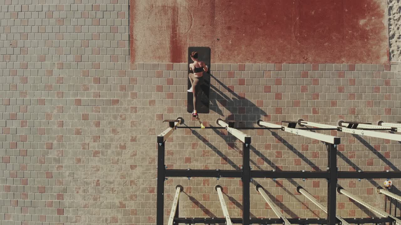 entrenamiento al aire libre. correas de suspensión. aero vista superior. mujer joven atlética está haciendo ejercicios de resistencia de todo el cuerpo usando cuerdas en bucle trx, en el campo deportivo al aire libre de la ciudad, gimnasio. entrenamiento de fitness al aire abierto. concepto de estilo de vida saludable. entrenamiento deportivo matutino en el