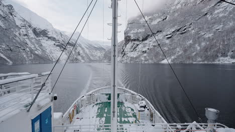 slow motion pov of a winter ferry boat ride in geirangerfjord to geiranger, norway, with snowy mountains and captivating fjord views