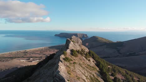 impressive flight above and along ana ferreira ridge peak mountain on island of porto santo with scenic view of vast blue ocean sea water, archipelago of madeira, portugal, overhead aerial approach