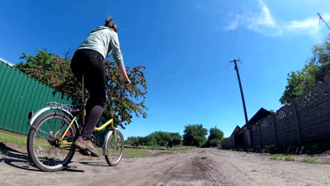 young woman riding vintage bicycle along a rural road in a village