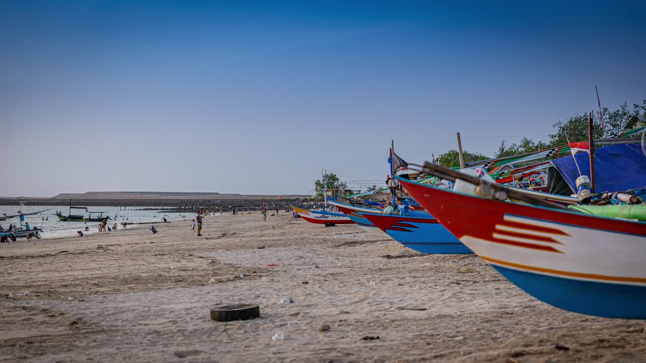 Timelapse of fishing boats leaving at sunset from Jimbaran Bay, Bali Indonesia looking towards the airport runway