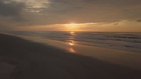 Atemberaubende-Luftaufnahme-Des-Strandes-Am-Frühen-Morgen-Mit-Atemberaubendem-Sonnenaufgang-Und-Ozean-Im-Hintergrund